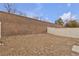 Backyard is surrounded by a rock wall and white fence at 9323 Leaping Deer Pl # 102, Las Vegas, NV 89178