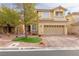 Two-story house with tan exterior, a large driveway, and landscaping at 10920 Fishers Island St, Las Vegas, NV 89141