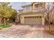 Two-story house featuring a tan exterior, a paved driveway and landscaping at 10920 Fishers Island St, Las Vegas, NV 89141