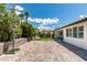 Wide backyard featuring brick pavers, a patch of grass, a windmill, and an outdoor seating area at 11268 Lavandou Dr, Las Vegas, NV 89141