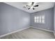 A cozy bedroom featuring gray walls, ceiling fan, wood-look floors, and a window with shutter-style blinds at 11268 Lavandou Dr, Las Vegas, NV 89141