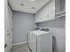 A gray laundry room with a modern white washer and dryer and white cabinetry at 11268 Lavandou Dr, Las Vegas, NV 89141