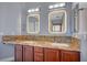 Bathroom with double sinks, framed mirrors with light features, granite counters, and wood cabinets at 11268 Lavandou Dr, Las Vegas, NV 89141