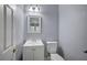 A well-lit powder room with gray walls, a white vanity, toilet, mirror, and chrome fixtures at 11268 Lavandou Dr, Las Vegas, NV 89141