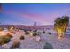 Landscaped backyard with stone pathway and lake view at dusk at 144 Stone Mesa Ct, Henderson, NV 89011