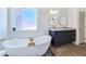 Bathroom featuring a modern soaking tub, window, decorative stone, and stylish vanity at 2280 S Pampa Ave, Pahrump, NV 89048