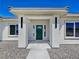 Close-up of the front entrance with a green door framed by pillars and modern lighting fixtures at 2280 S Pampa Ave, Pahrump, NV 89048