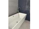 Close up of modern white tub with stainless steel fixtures, surrounded by penny tile at 7237 William Anders Ave, Las Vegas, NV 89145