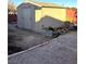 The outdoor shed features wood paneling and a shingled roof, surrounded by a paved backyard with foliage at 7415 Constantinople Ave, Las Vegas, NV 89129