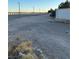 A dirt area near a community wall featuring dry weeds and street lights in the distance at 7415 Constantinople Ave, Las Vegas, NV 89129