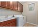 Functional laundry room with sink, cabinetry and a modern, front-loading washing machine at 1172 Via Della Costrella, Henderson, NV 89011