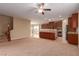 Open-concept living room with carpet flooring flowing into kitchen with stainless steel appliances and ceiling fan at 1172 Via Della Costrella, Henderson, NV 89011