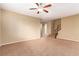 Neutral carpeted living room showcasing a ceiling fan and a view of the staircase to the upper level at 1172 Via Della Costrella, Henderson, NV 89011