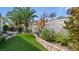 Landscaped backyard with a stone retaining wall and lush grass at 2107 Inverness Dr, Henderson, NV 89074