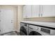 Bright laundry room with a modern washer and dryer set and storage cabinets above at 2107 Inverness Dr, Henderson, NV 89074