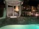 Elegant pool area at night with a stone gazebo and waterfall feature at 2107 Inverness Dr, Henderson, NV 89074