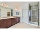 Bathroom featuring granite countertops, double sinks, decorative lighting, and a walk-in shower with glass doors at 217 Via Luna Rosa Ct, Henderson, NV 89011