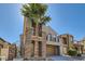 Two-story home showcasing neutral stucco, stacked stone, balcony, decorative trim, arched entry, two-car garage and mature palm tree at 217 Via Luna Rosa Ct, Henderson, NV 89011