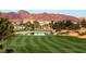 Scenic golf course with lush green fairways, pond, palm trees, and mountain views, perfect for a relaxing day on the green at 217 Via Luna Rosa Ct, Henderson, NV 89011