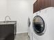 Laundry room with dark brown tile floor, modern washer and dryer, and utility sink at 2364 Boretto St, Henderson, NV 89044