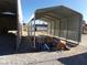 Metal carport on a gravel lot providing covered storage next to other outbuildings and debris at 3381 W Simkins Rd, Pahrump, NV 89060