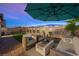 Inviting backyard features a cozy seating area under an umbrella, a manicured lawn, and a privacy wall at 7073 Range Valley St, North Las Vegas, NV 89084