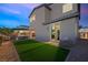 Dusk view of a backyard featuring artificial grass, a patio, and outdoor seating at 7073 Range Valley St, North Las Vegas, NV 89084