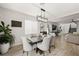 A dining room boasts a dark wood table, six upholstered chairs, and a modern, rectangular chandelier at 7073 Range Valley St, North Las Vegas, NV 89084