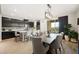 Dining area with a view of the open kitchen, featuring dark cabinets, a breakfast bar, and an elegant modern light fixture at 7073 Range Valley St, North Las Vegas, NV 89084