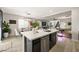 Stylish kitchen island with stainless appliances, quartz countertops, dark cabinetry, and a dining area at 7073 Range Valley St, North Las Vegas, NV 89084