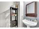 Bathroom featuring a pedestal sink with a mirror, a shelf for towels, and a gray color scheme at 7288 Olsen Farm St, Las Vegas, NV 89131