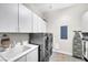 Well-lit laundry room with washer, dryer, utility sink, and ample cabinet space at 7288 Olsen Farm St, Las Vegas, NV 89131