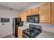 Modern kitchen with granite countertops, black appliances, and light wood cabinets at 8555 W Russell Rd # 1101, Las Vegas, NV 89113