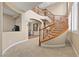 Grand curved staircase with wooden banister opens to the dining room for seamless entertaining at 1067 Via Saint Andrea Pl, Henderson, NV 89011