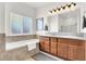 Bright bathroom featuring a separate tub and dual sink vanity with wood cabinets at 1920 Cavalry St, Pahrump, NV 89048