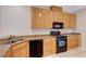 Galley kitchen with light wood cabinets, granite counters, and black appliances at 3968 Moon Tango St, Las Vegas, NV 89129