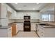 Modern kitchen with white cabinets, granite counters, and black appliances at 422 Waterbrook Dr, Henderson, NV 89015