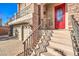 Close up of home's entrance with ornate red door, brickwork, and iron railing at 5490 Tulip Hill Ave, Las Vegas, NV 89141