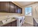 Laundry room with washer, dryer, sink, and dark wood cabinets at 5490 Tulip Hill Ave, Las Vegas, NV 89141