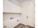 Functional laundry room with upper cabinets, wood-look tile flooring, and a door to the exterior at 65 Ibiza Lake Dr, Henderson, NV 89011