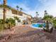 Backyard featuring a sparkling pool, palm trees and gravel landscaping with covered patio at 908 Primrose Ln, Henderson, NV 89011