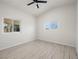 Bedroom featuring light wood-look floors, ceiling fan, and views through two windows at 908 Primrose Ln, Henderson, NV 89011