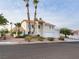 Two-story stucco home featuring a three car garage, desert landscaping and mature palm trees at 908 Primrose Ln, Henderson, NV 89011