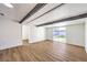 Open-concept living room featuring wood-look floors, black beams, and sliding glass doors to the backyard at 701 N Yale St, Las Vegas, NV 89107