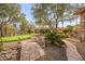 Spacious backyard with mature trees, desert landscaping, putting green, and stone walkway leading to the house at 7450 Via Olivero Ave, Las Vegas, NV 89117