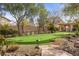 Beautiful backyard featuring an artificial putting green with mature landscaping and custom hardscape at 7450 Via Olivero Ave, Las Vegas, NV 89117