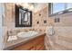 Well lit powder room with decorative backsplash, black framed mirror, and natural light at 7450 Via Olivero Ave, Las Vegas, NV 89117