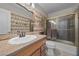 Bathroom with a tiled shower, glass door, decorative mirror, sink, and granite countertop at 7450 Via Olivero Ave, Las Vegas, NV 89117