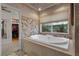 Relaxing bathroom with a soaking tub nestled under a window with a decorative tile surround and walk-in closet at 7450 Via Olivero Ave, Las Vegas, NV 89117