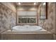 Bright bathroom with a relaxing soaking tub and neutral-toned tile and a backyard view at 7450 Via Olivero Ave, Las Vegas, NV 89117